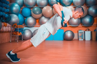 Genç adam bir spor salonunda trx devreye girer