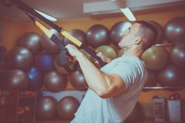 Genç adam bir spor salonunda trx devreye girer