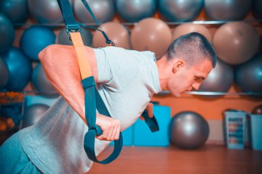 Genç adam bir spor salonunda trx devreye girer