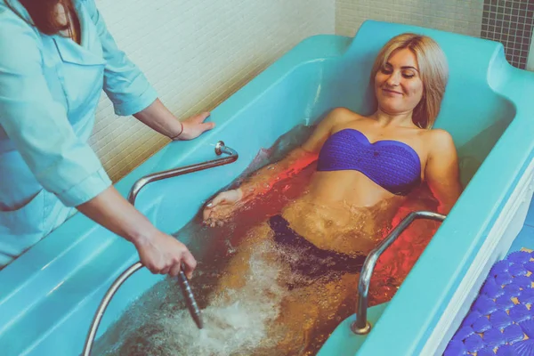 Blonde woman relaxing in spa salon during underwater massage