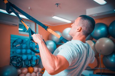 Genç adam bir spor salonunda trx devreye girer