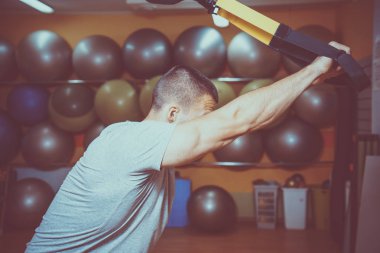 Genç adam bir spor salonunda trx devreye girer
