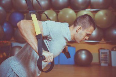 Genç adam bir spor salonunda trx devreye girer
