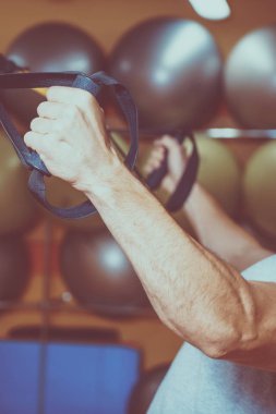 Genç adam bir spor salonunda trx devreye girer
