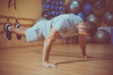 Genç adam bir spor salonunda trx devreye girer