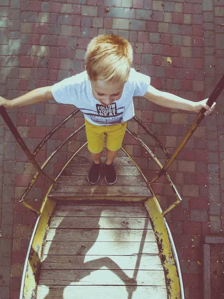 The boy is riding on a swing-boat — Stock Photo, Image