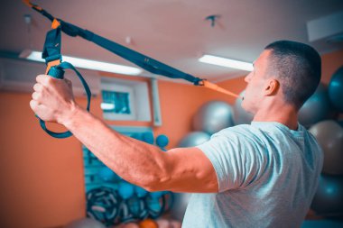 Genç adam bir spor salonunda trx devreye girer