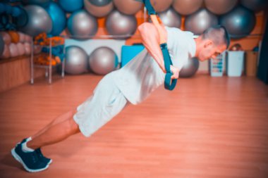Genç adam bir spor salonunda trx devreye girer
