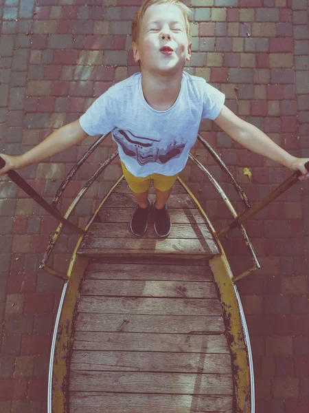 The boy is riding on a swing-boat — Stock Photo, Image