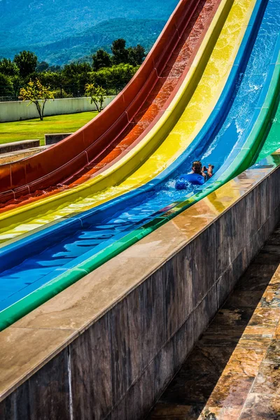 O menino monta um slide no parque aquático — Fotografia de Stock