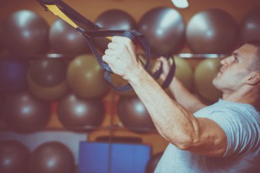 Genç adam bir spor salonunda trx devreye girer