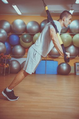 Genç adam bir spor salonunda trx devreye girer