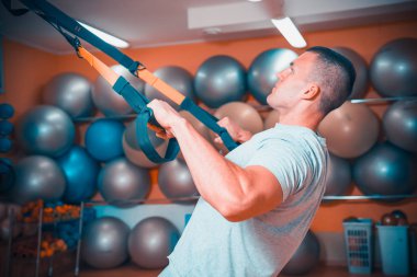 Genç adam bir spor salonunda trx devreye girer