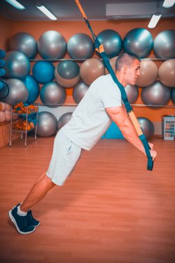 Genç adam bir spor salonunda trx devreye girer