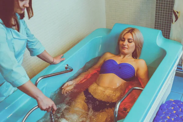 Blonde woman relaxing in spa salon during underwater massage