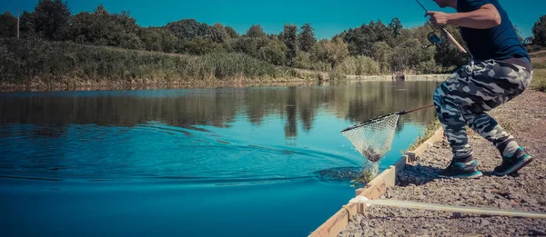 Pescador captura trucha arco iris del lago — Foto de Stock