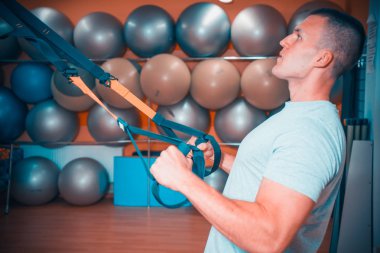 Genç adam bir spor salonunda trx devreye girer