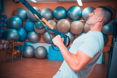 Genç adam bir spor salonunda trx devreye girer