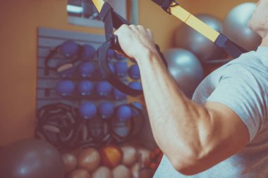 Genç adam bir spor salonunda trx devreye girer