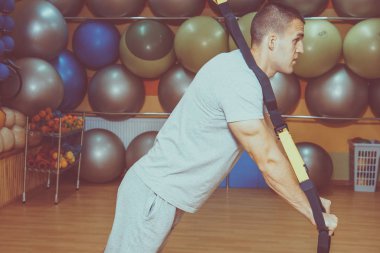 Genç adam bir spor salonunda trx devreye girer