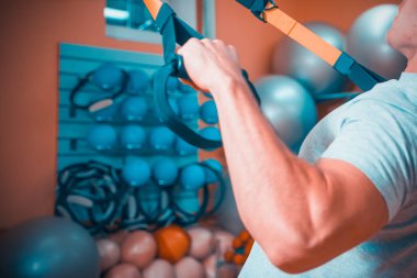 Genç adam bir spor salonunda trx devreye girer