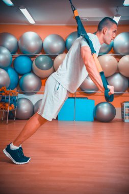 Genç adam bir spor salonunda trx devreye girer