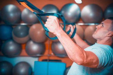 Genç adam bir spor salonunda trx devreye girer