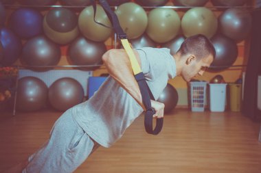 Genç adam bir spor salonunda trx devreye girer