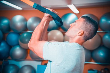 Genç adam bir spor salonunda trx devreye girer