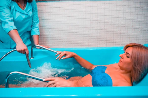 Blonde woman relaxing in spa salon during underwater massage