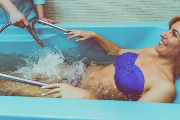 Blonde woman relaxing in spa salon during underwater massage