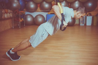 Genç adam bir spor salonunda trx devreye girer