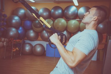 Genç adam bir spor salonunda trx devreye girer