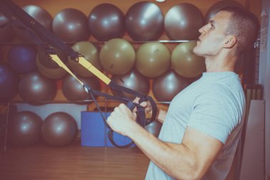 Genç adam bir spor salonunda trx devreye girer