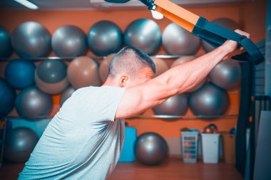 Genç adam bir spor salonunda trx devreye girer