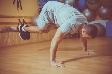 Genç adam bir spor salonunda trx devreye girer