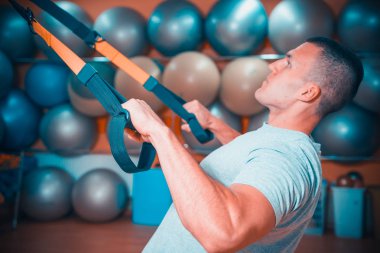 Genç adam bir spor salonunda trx devreye girer