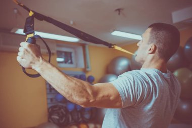 Genç adam bir spor salonunda trx devreye girer