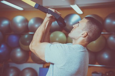 Genç adam bir spor salonunda trx devreye girer