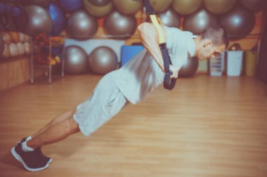 Genç adam bir spor salonunda trx devreye girer