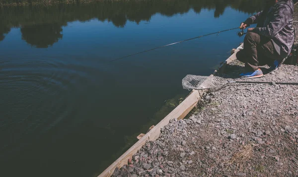 Ψαράς αλιευμάτων ιριδίζουσα πέστροφα από λίμνη — Φωτογραφία Αρχείου