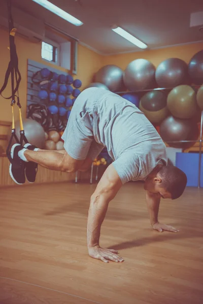 Ung man är engagerad i ett gym i trx — Stockfoto