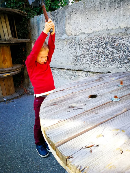 Der Junge schlägt mit einem Hammer auf den Tisch — Stockfoto