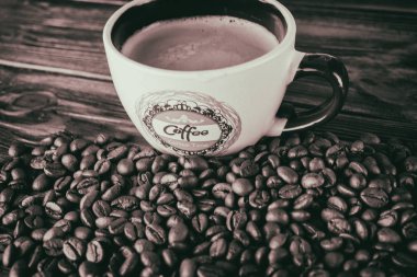 Tahta arka planda bir fincan kahve ve kahve çekirdeği.