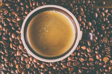 Tahta arka planda bir fincan kahve ve kahve çekirdeği.