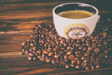 Tahta arka planda bir fincan kahve ve kahve çekirdeği.