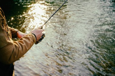 Balıkçı bir alabalık bir dağ nehir üzerinde yakalar.