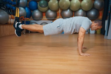 Genç adam bir spor salonunda trx devreye girer