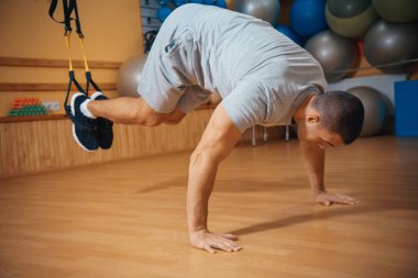 Genç adam bir spor salonunda trx devreye girer