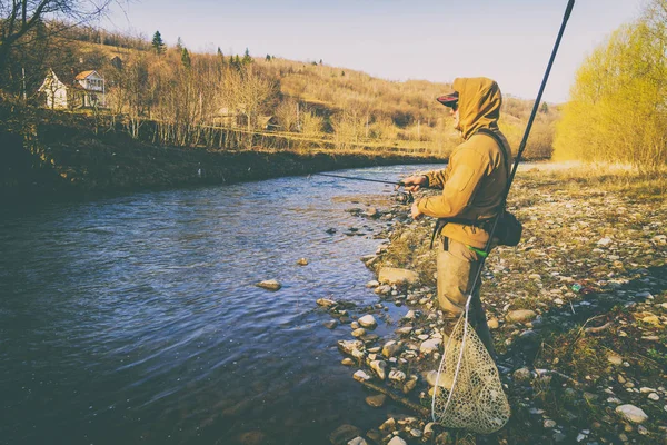 Pescatore cattura una trota su un fiume di montagna — Foto Stock